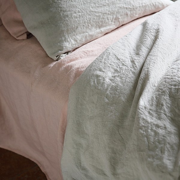 Neutral linen sheets arranged on a bed