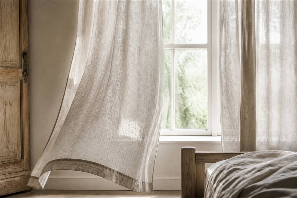 Natural linen curtains filtering daylight in a rustic bedroom