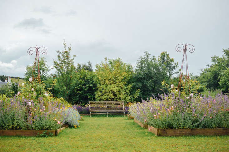 Flowering herb beds and a wooden bench at the Secret Herb Garden