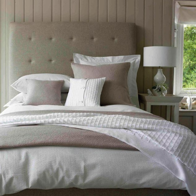 Soft neutral linen bedding layered with pillows and a light throw
