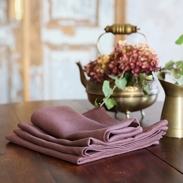 Folded mauve linen napkins ready for a table setting