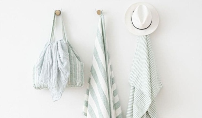 Mint-striped linen beach towels hanging with a summer hat