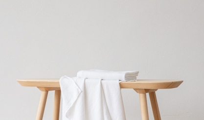 Soft white linen towel draped over a wooden bench for gentle drying