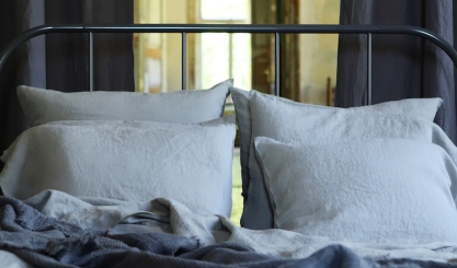 Natural linen flat and fitted sheets arranged on a calm neutral bed