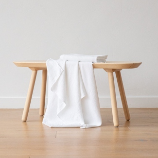 Soft white linen towel draped over a wooden bench for gentle drying