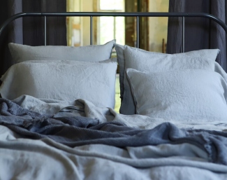 Natural linen flat and fitted sheets arranged on a calm neutral bed